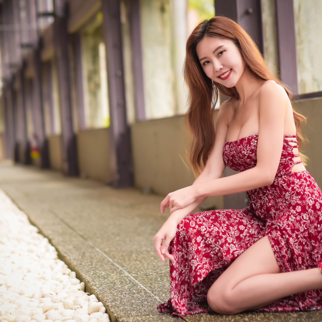 Улыбающаяся азиатка в красном платье у окна 