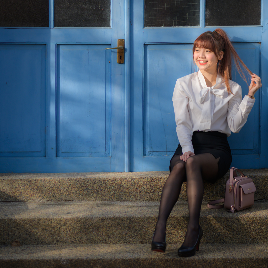 Улыбающаяся азиатка сидит на ступеньках