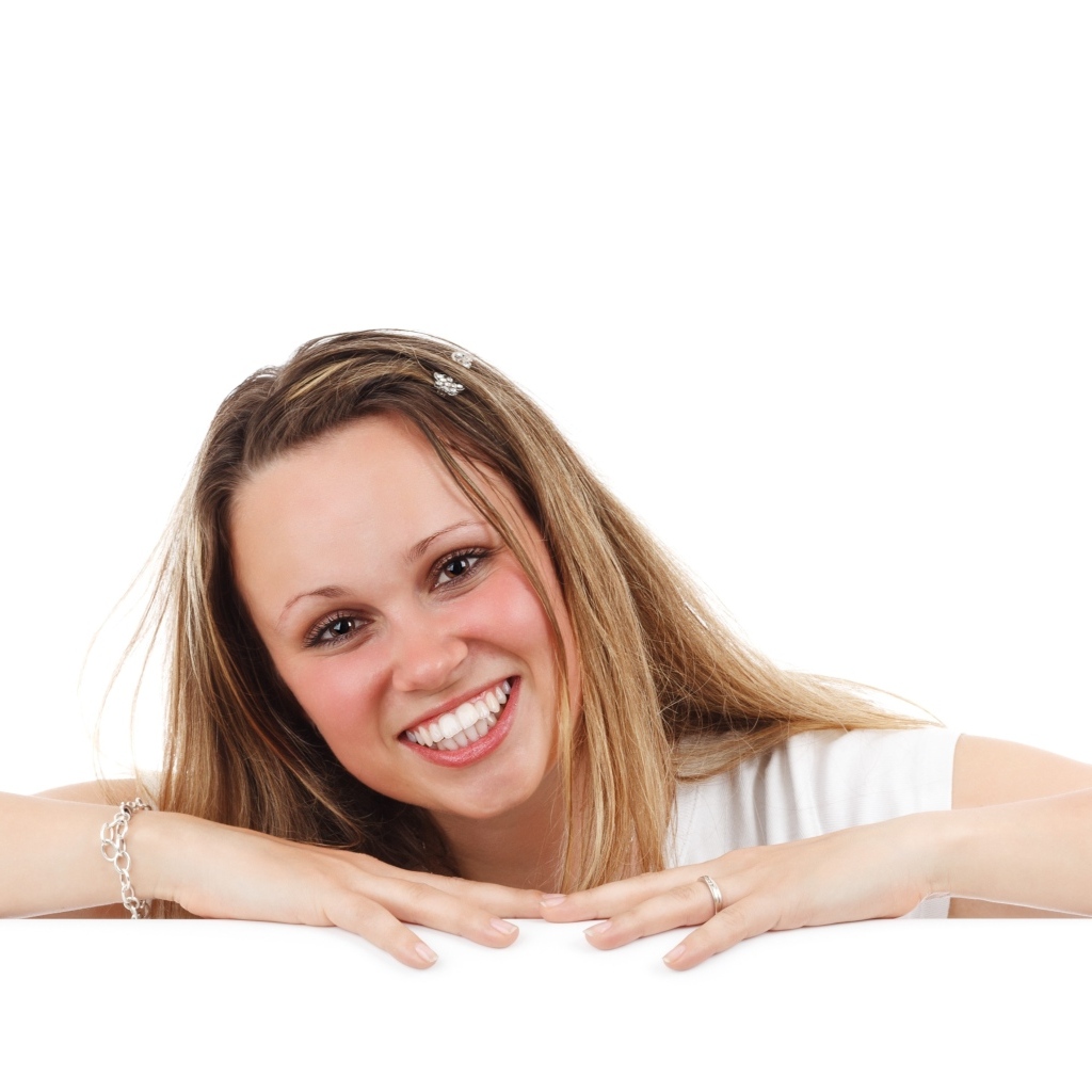 Улыбающаяся девушка сидит на белом фоне