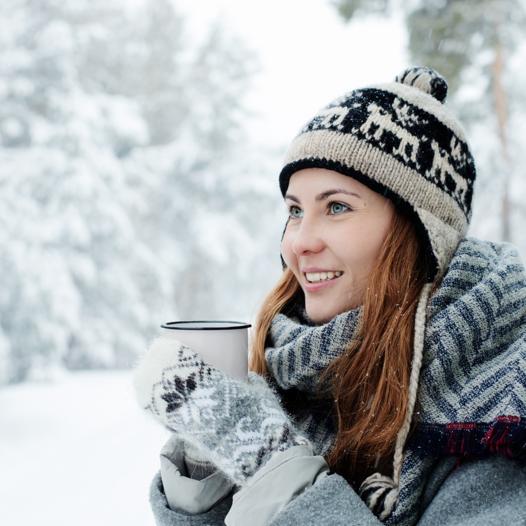 Улыбающаяся девушка с чашкой кофе зимой