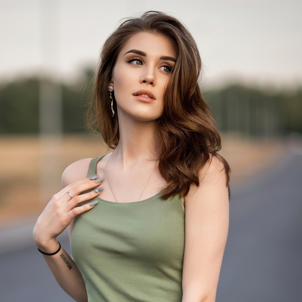 Нежная длинноволосая девушка стоит на дороге