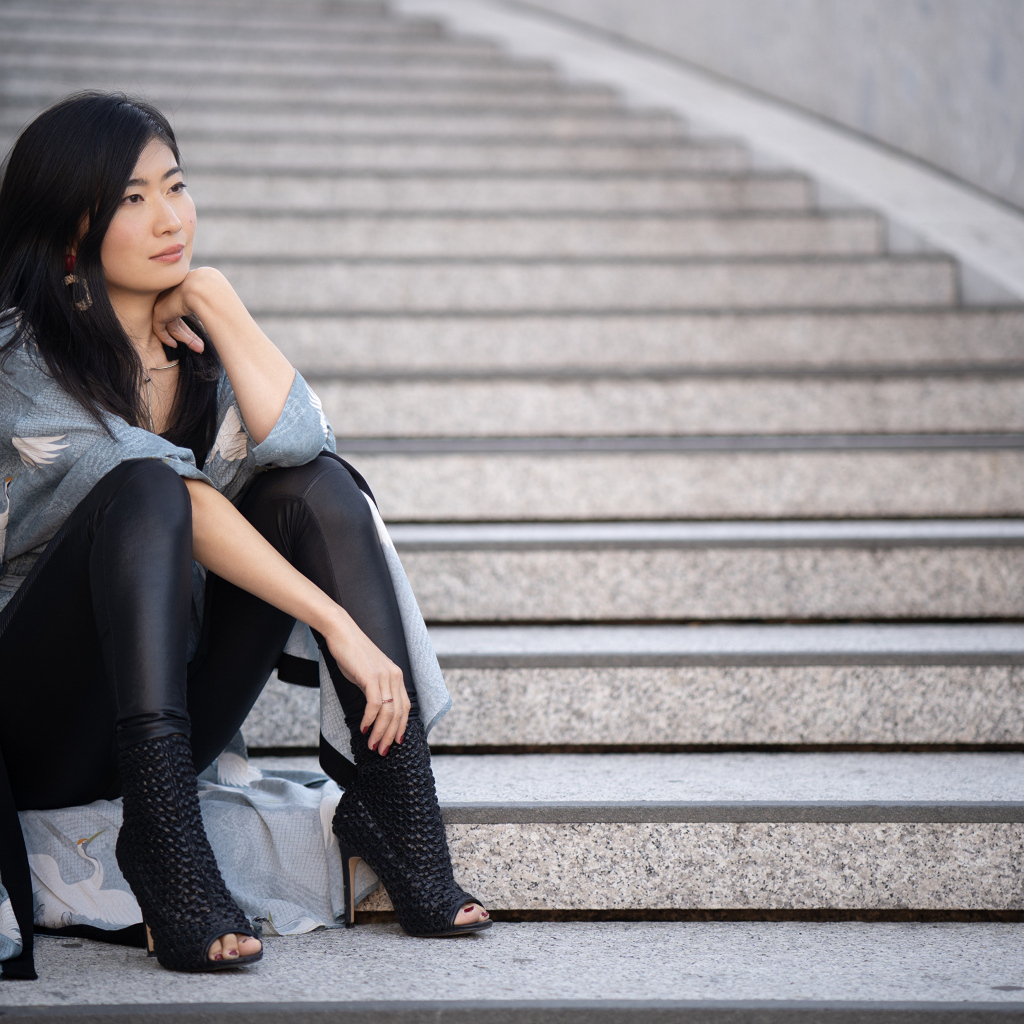 Задумчивая девушка азиатка сидит на ступеньках
