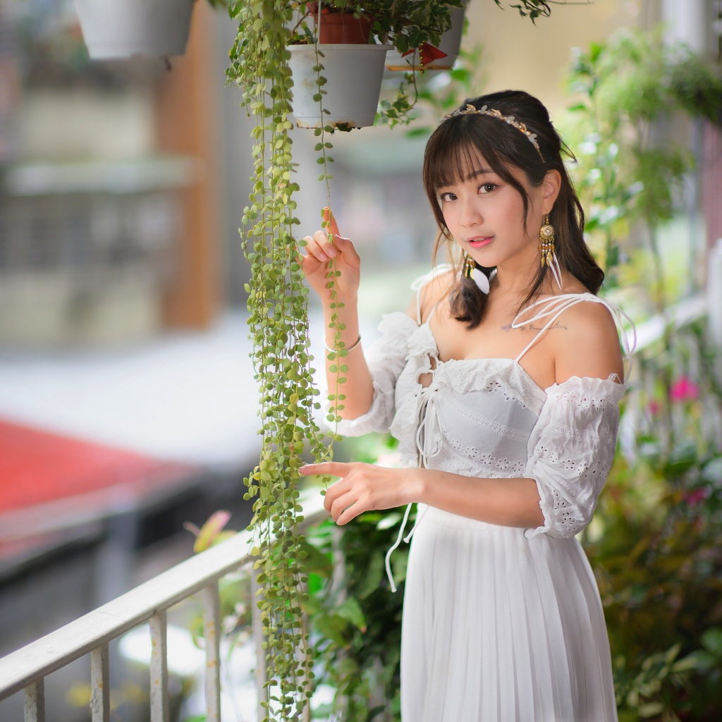 Молодая азиатка в белом платье у растений