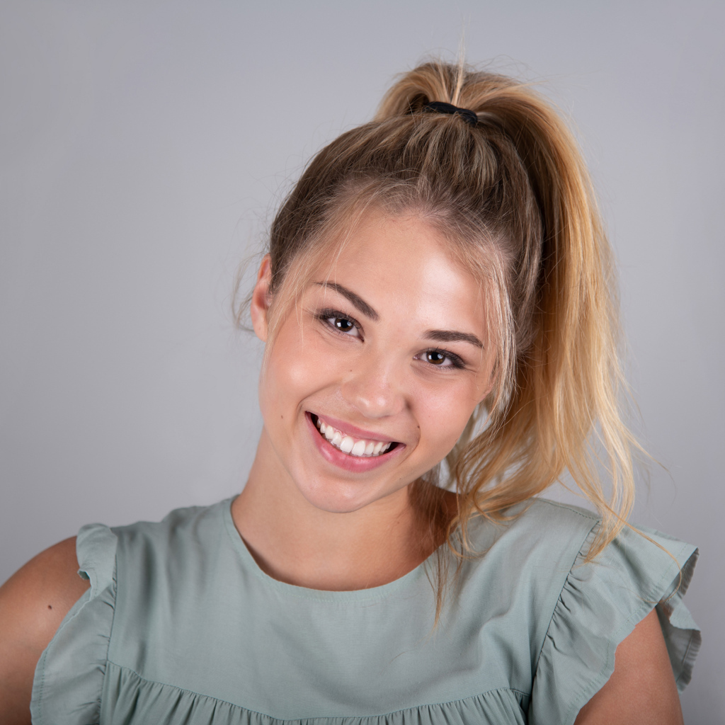 Молодая девушка блондинка на сером фоне