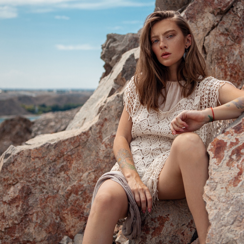 Молодая девушка сидит на камнях