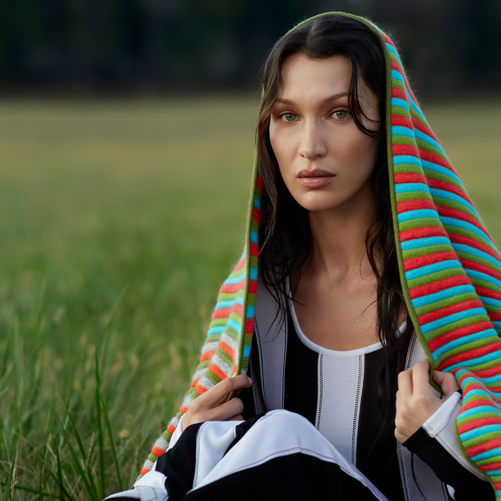 Модель Белла Хадид сидит на траве под пледом