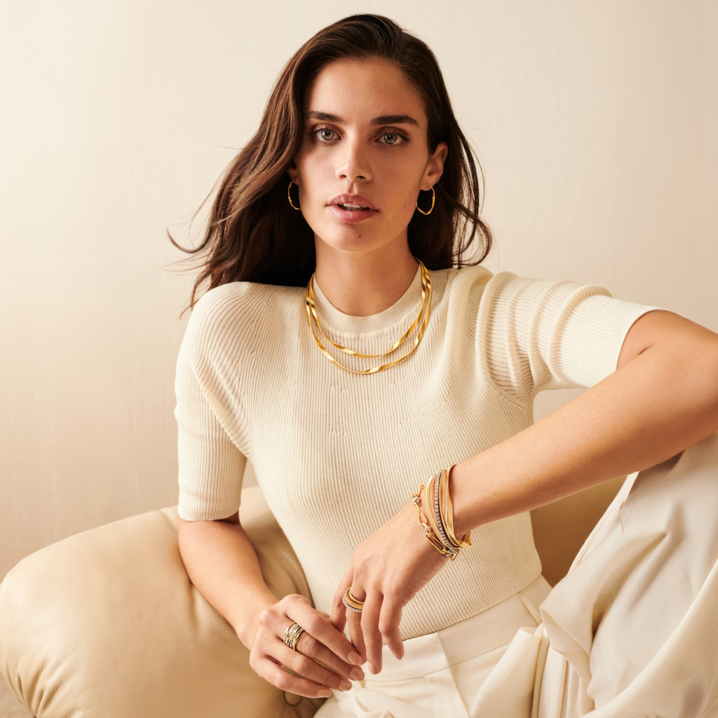 Модель Сара Сампайо в белом наряде сидит в кресле