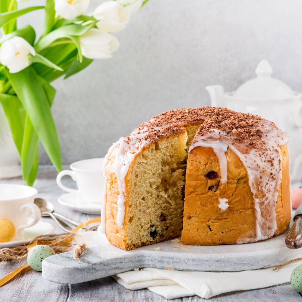 Пасхальный кулич на столе с букетом тюльпанов и сладостями
