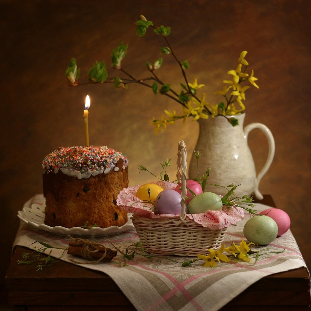 Кулич со свечой и крашеными яйцами на столе на Пасху