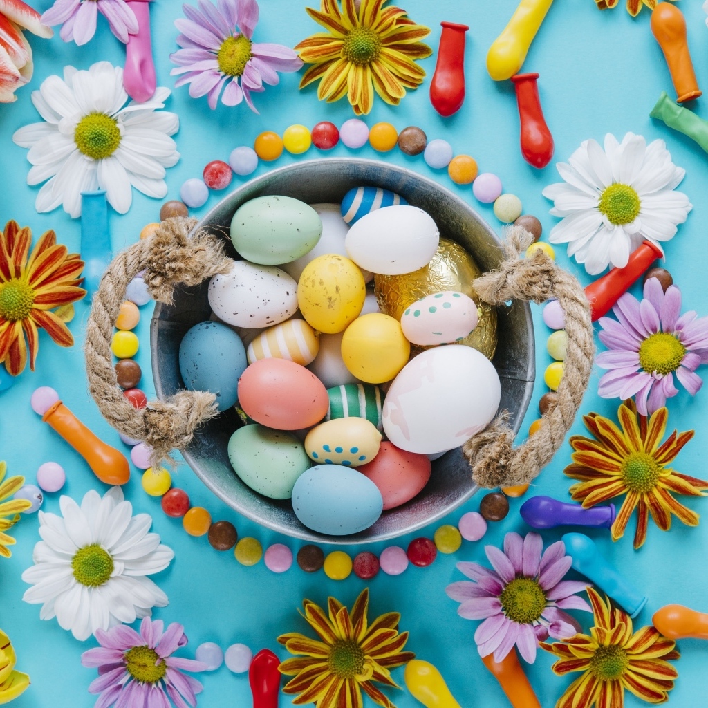 Разноцветные яйца с цветами на голубом фоне на Пасху