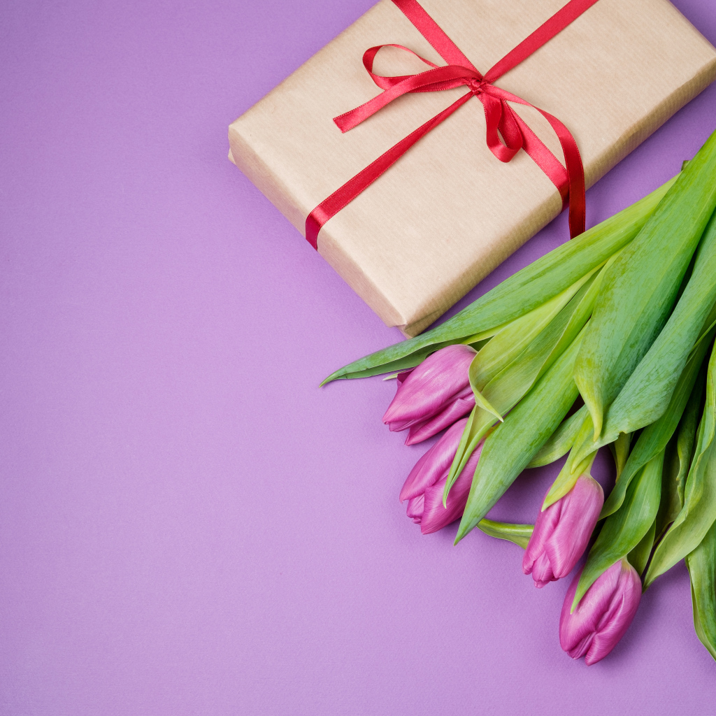 Подарок и букет красивых тюльпанов на сиреневом фоне