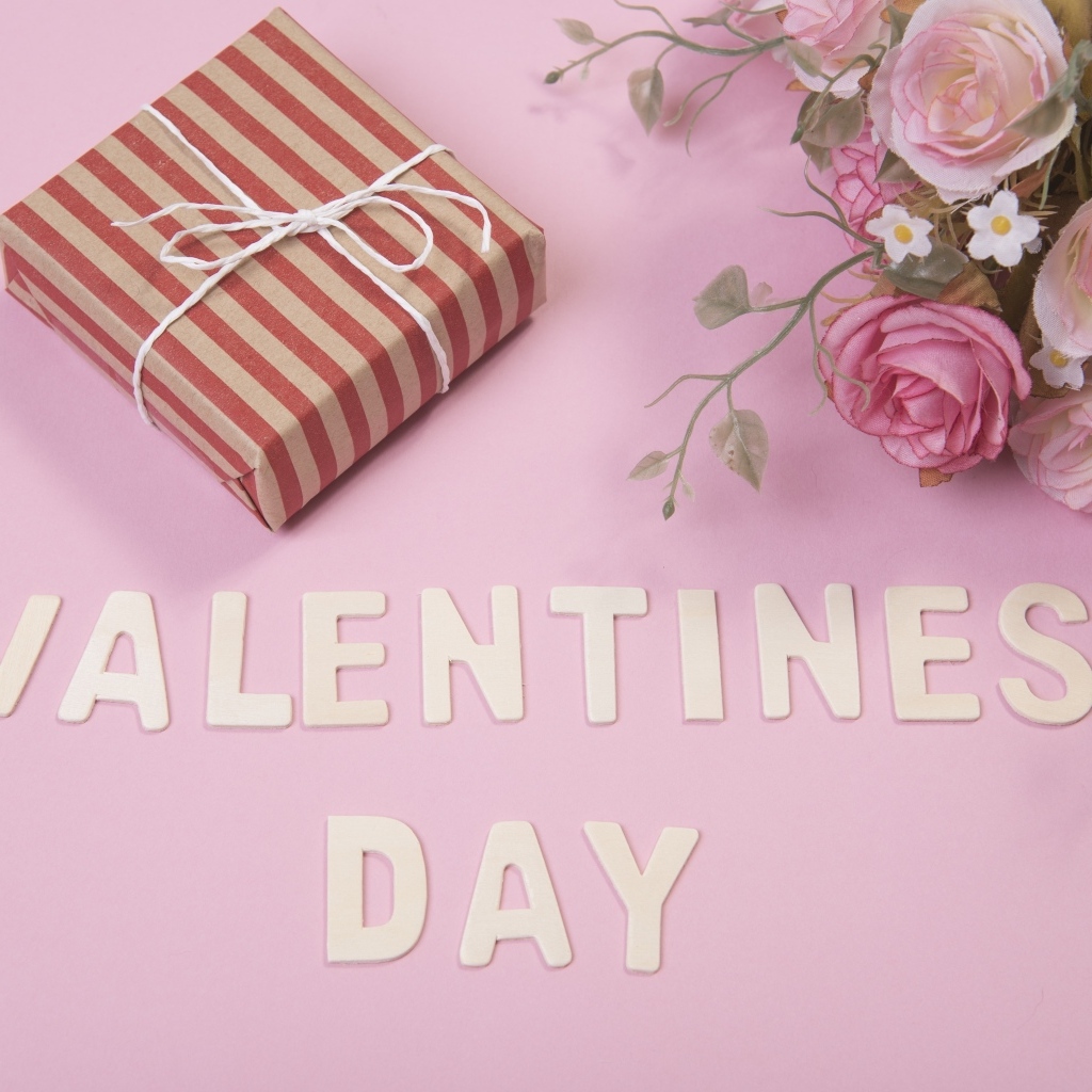 Flowers and gift on pink background for Valentine's Day
