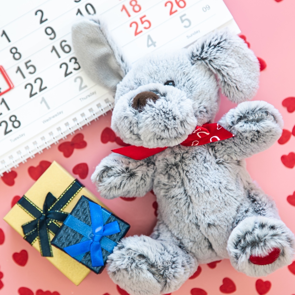 Игрушка и календарь на розовом фоне