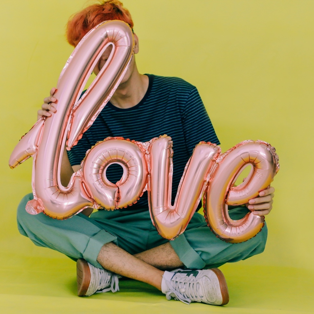 Мужчина держит шарики с надписью любовь