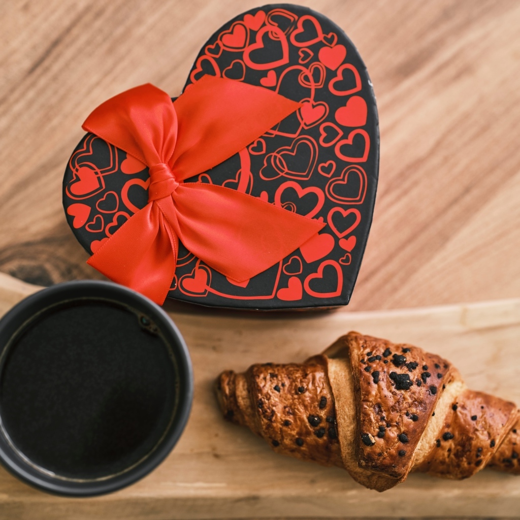 Коробка в форме сердца, кофе и круассан на столе