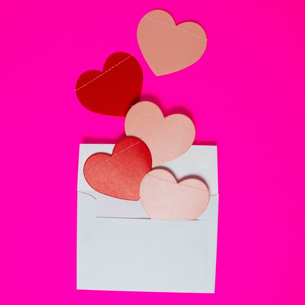 Сердечки с белым конвертом на розовом фоне