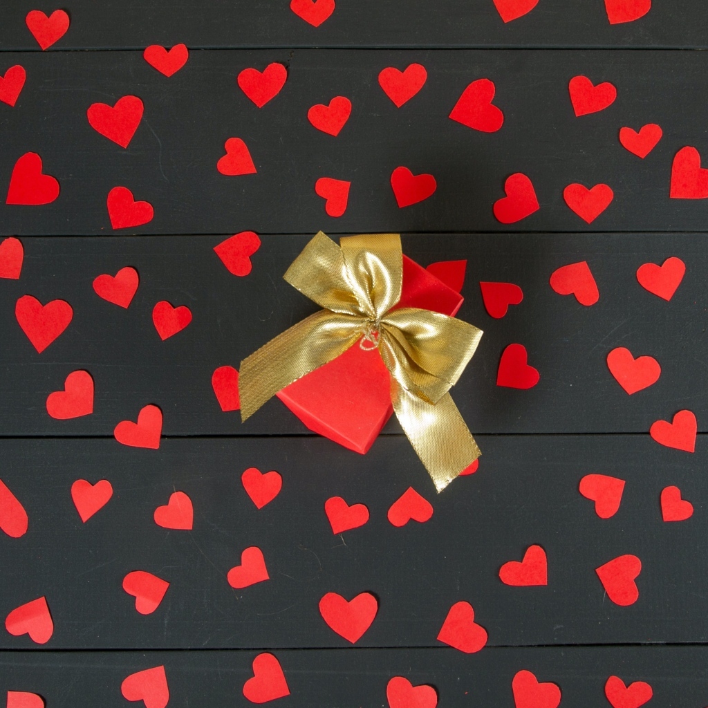 Много маленьких бумажных сердечек с подарком на столе