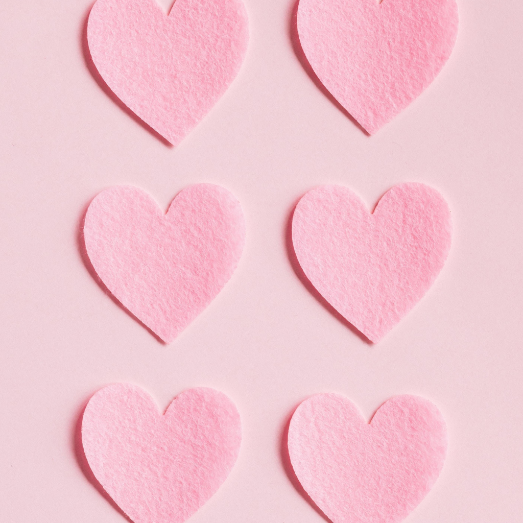 Маленькие бумажные сердечки на розовом фоне