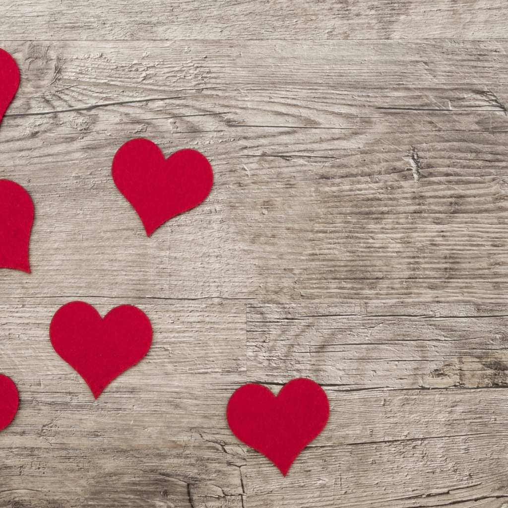 Маленькие красные сердечки на деревянном фоне