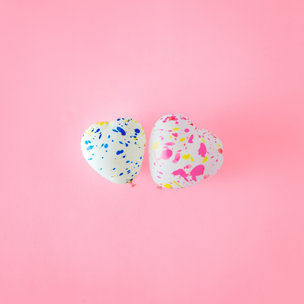 Два шарика в форме сердца на розовом фоне