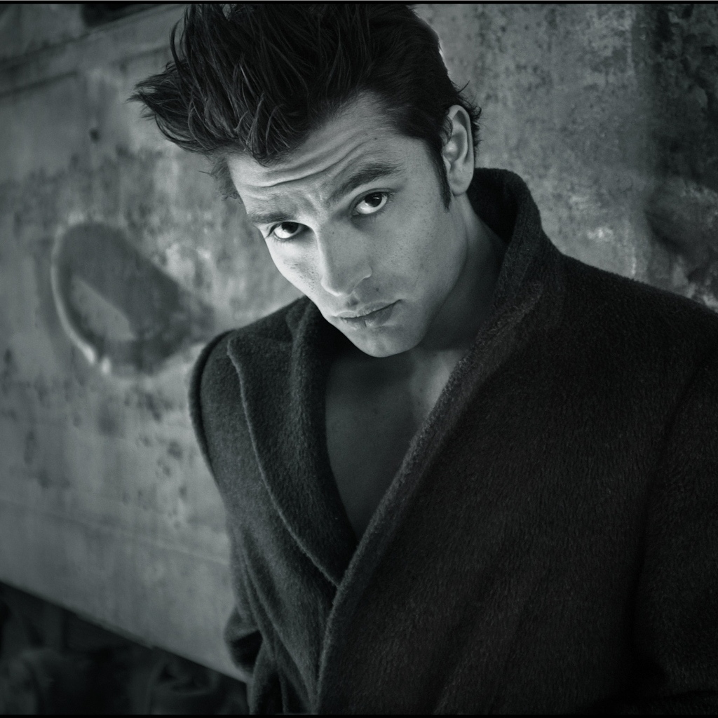 Красивый мужчина в черном пальто у стены