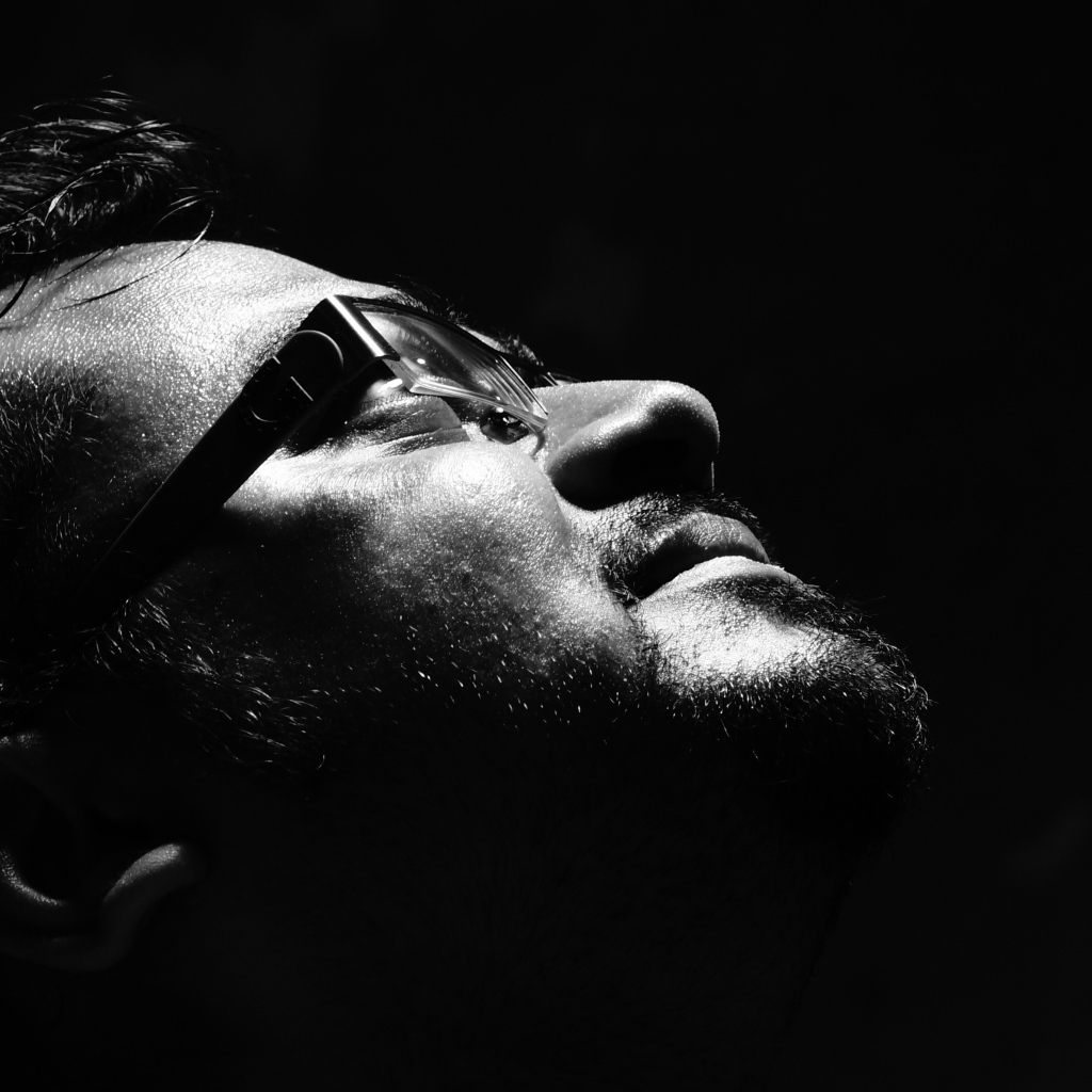 Мужчина в очках смотрит вверх на черном фоне