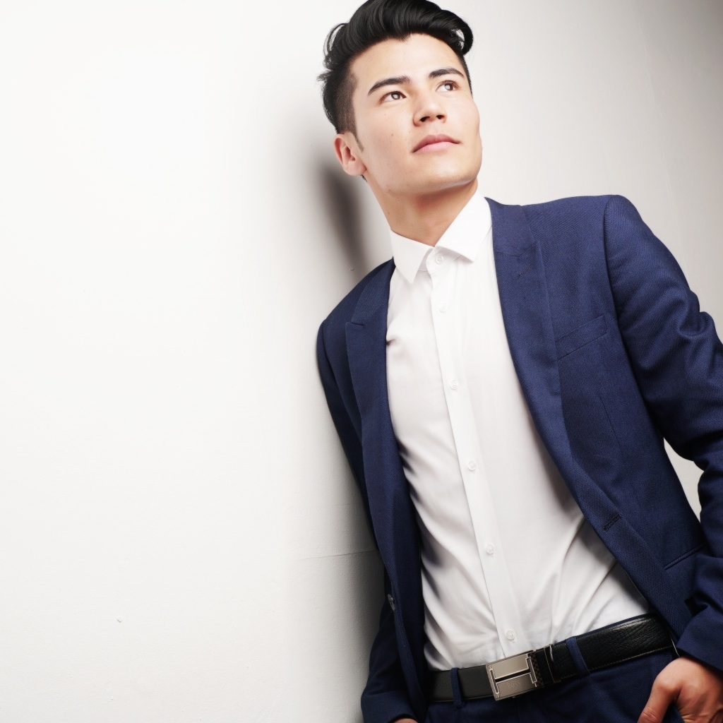 Молодой мужчина в костюме у стены