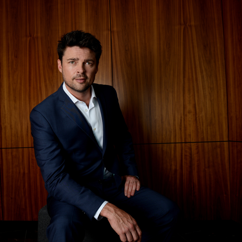 Актер Карл Урбан в костюме на фоне стены