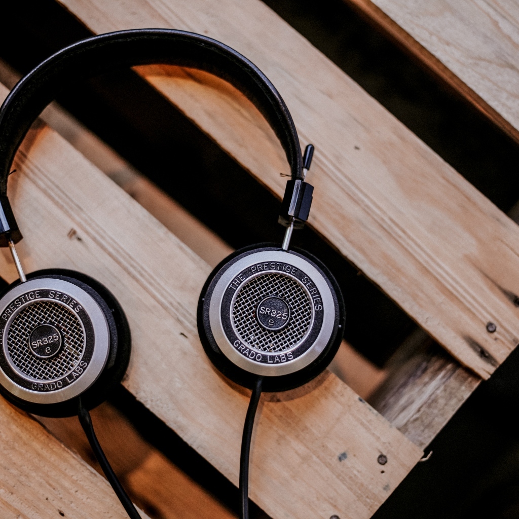 Старые наушники лежат на деревянной лавке