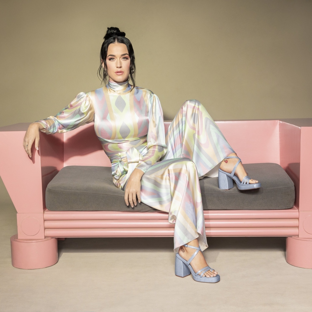 Певица Кэти Перри сидит на розовом диване