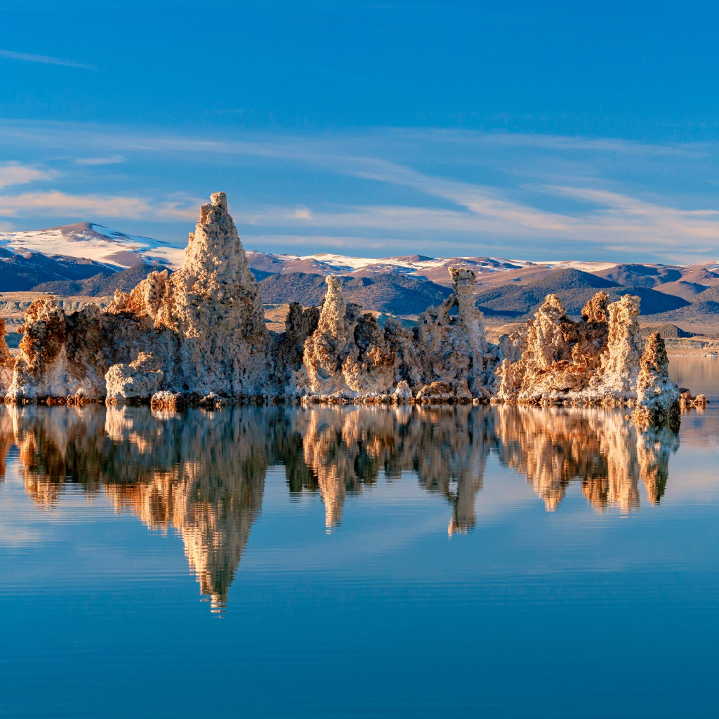 Острые скалы отражаются в тихой воде озера