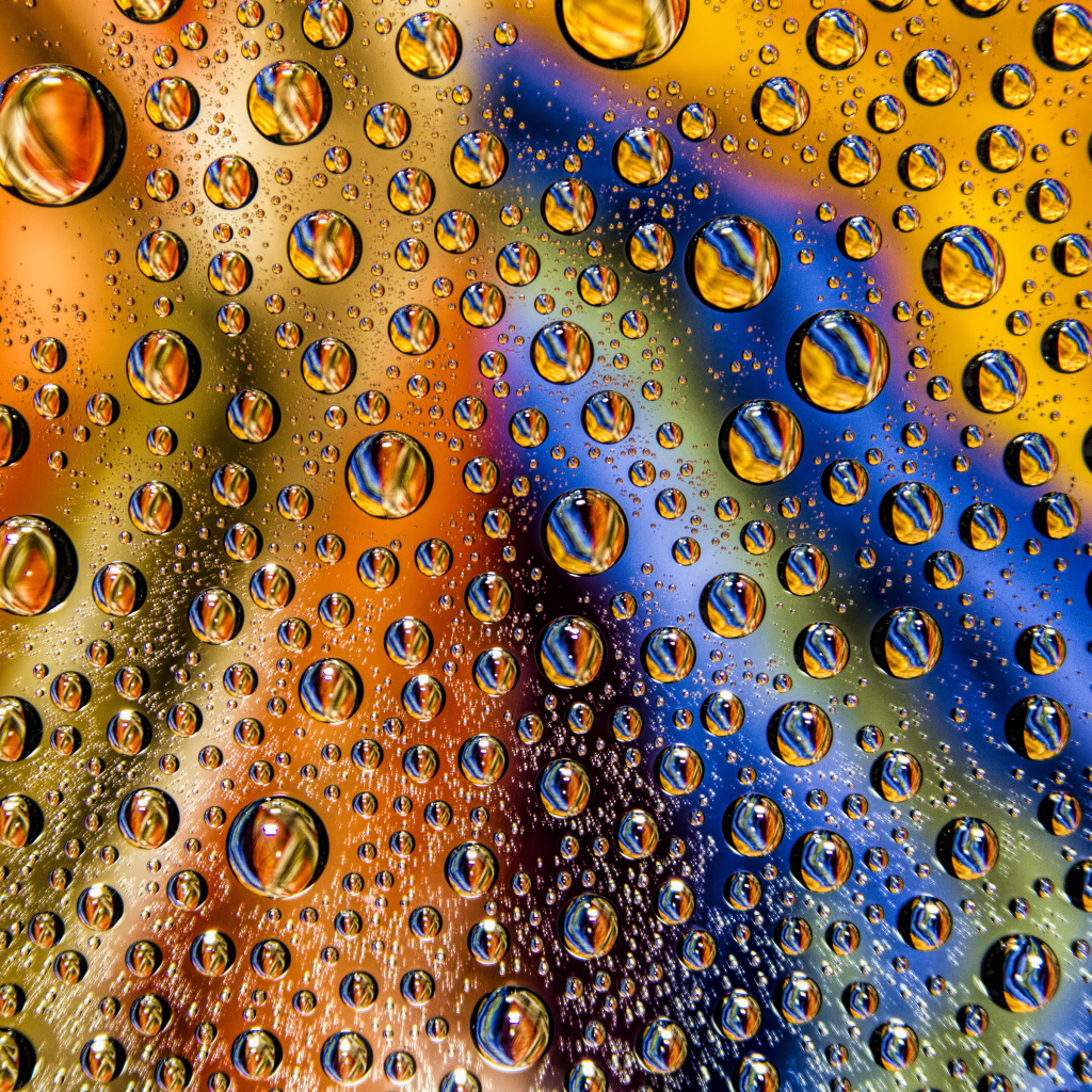 Капли воды на разноцветном стеклянном фоне