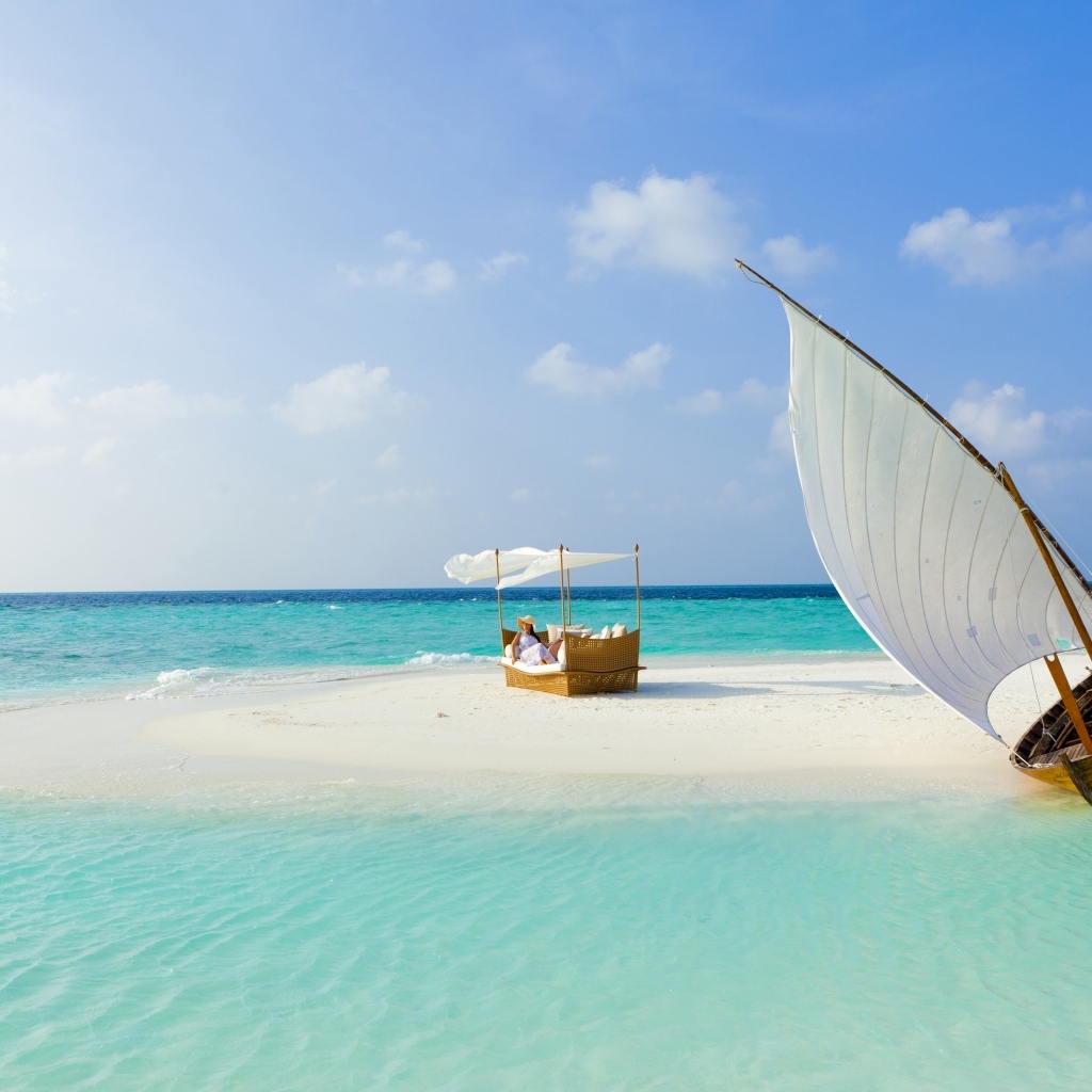 Лодка стоит на белом песке у голубого океана