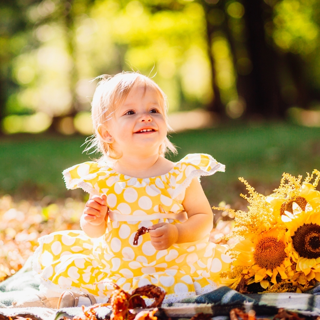 Малышка с цветами подсолнуха на траве