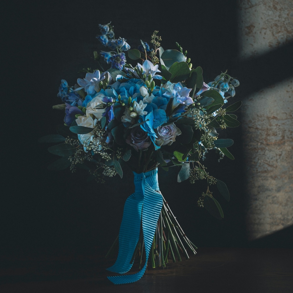 Красивый букет цветов с голубой лентой у стены