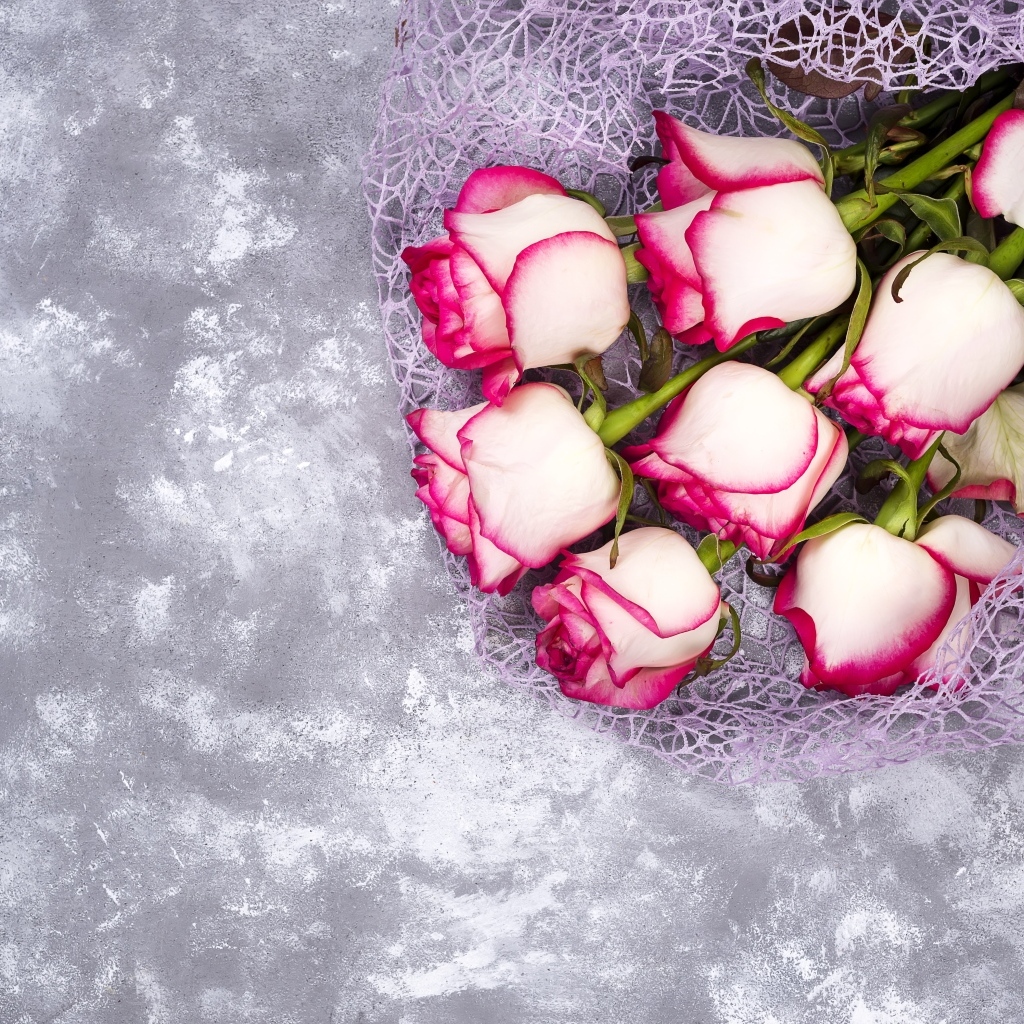 Красивый букет роз в упаковке на сером столе