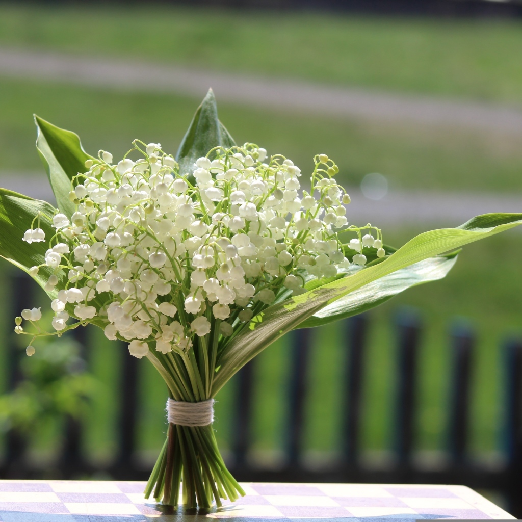 Красивый букет белых ландышей на столе в вазе