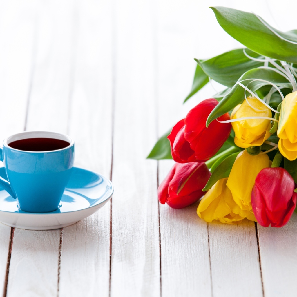 Голубая чашка на столе с букетом тюльпанов