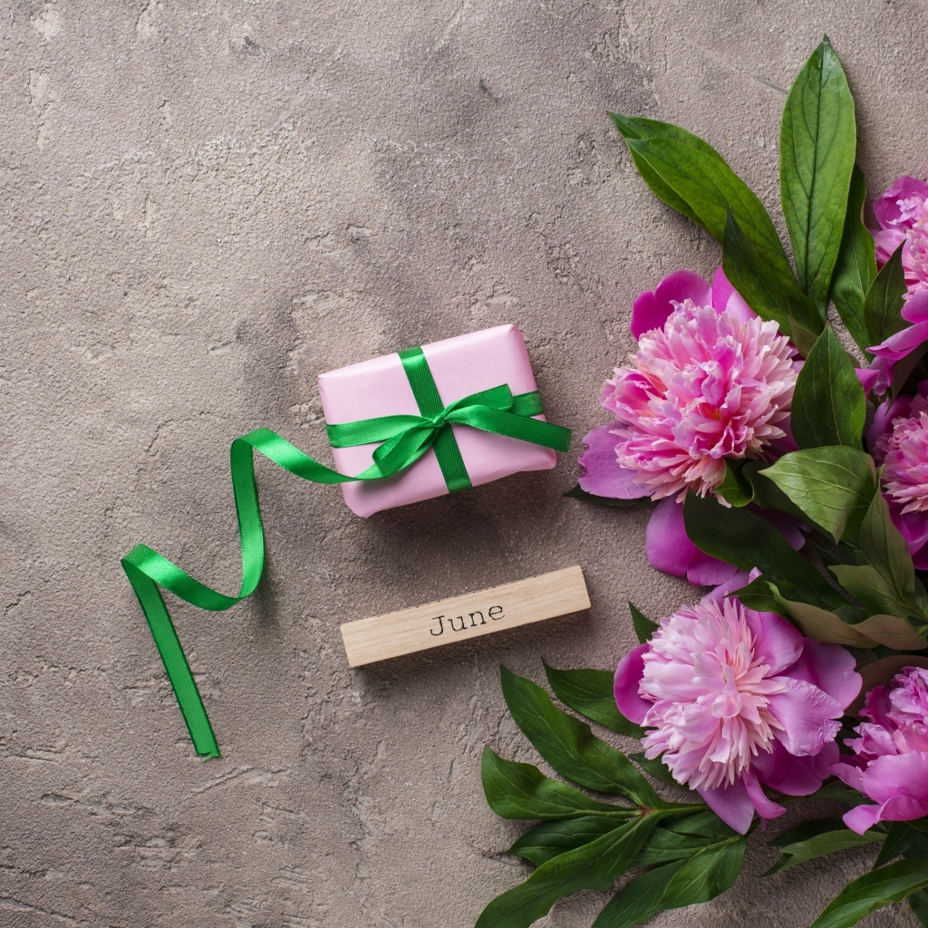 Букет розовых пионов с подарком на сером столе