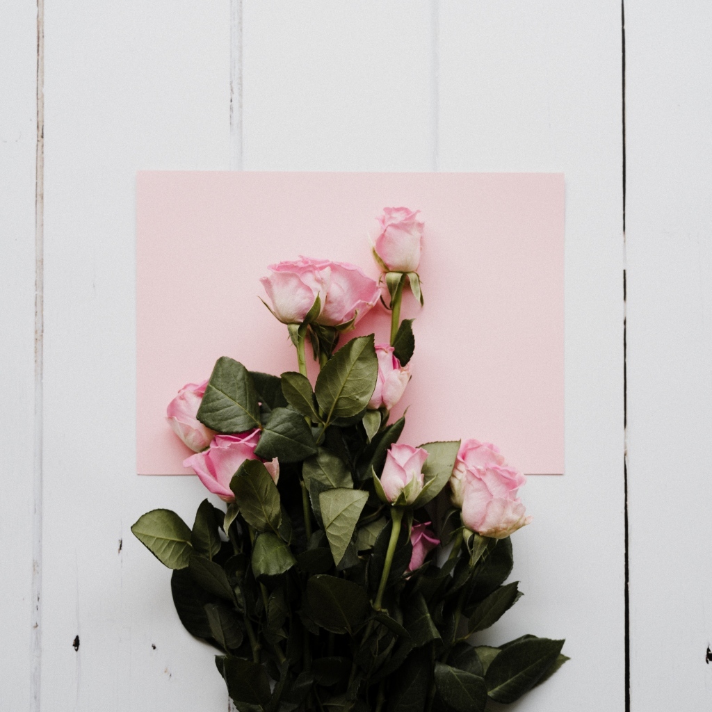 Букет роз с розовым листом бумаги на столе