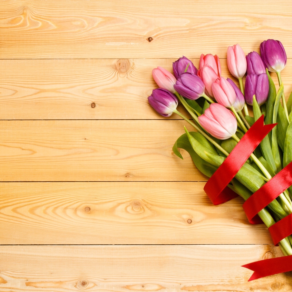 Большой букет тюльпанов с красной лентой на деревянном фоне
