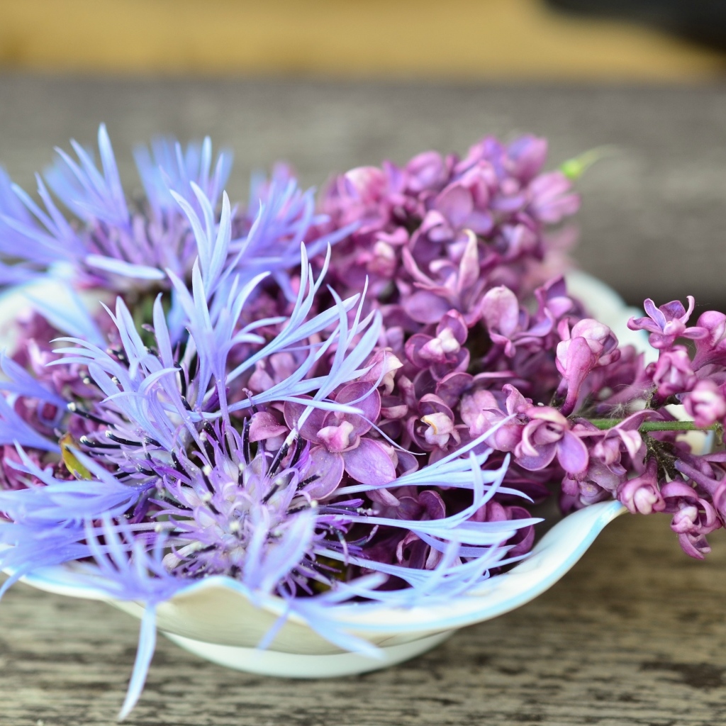 Цветы сирени и василька в вазе на столе