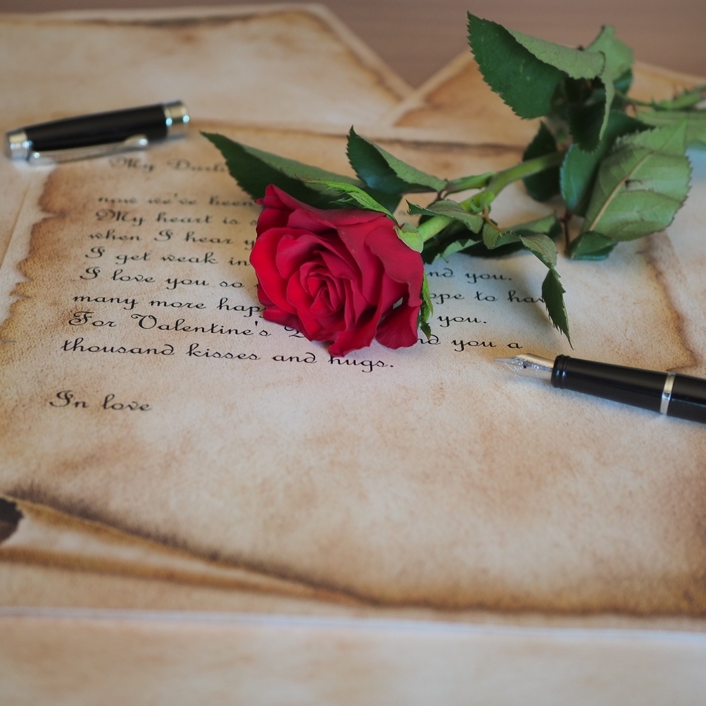 Красная роза с запиской и ручкой на столе