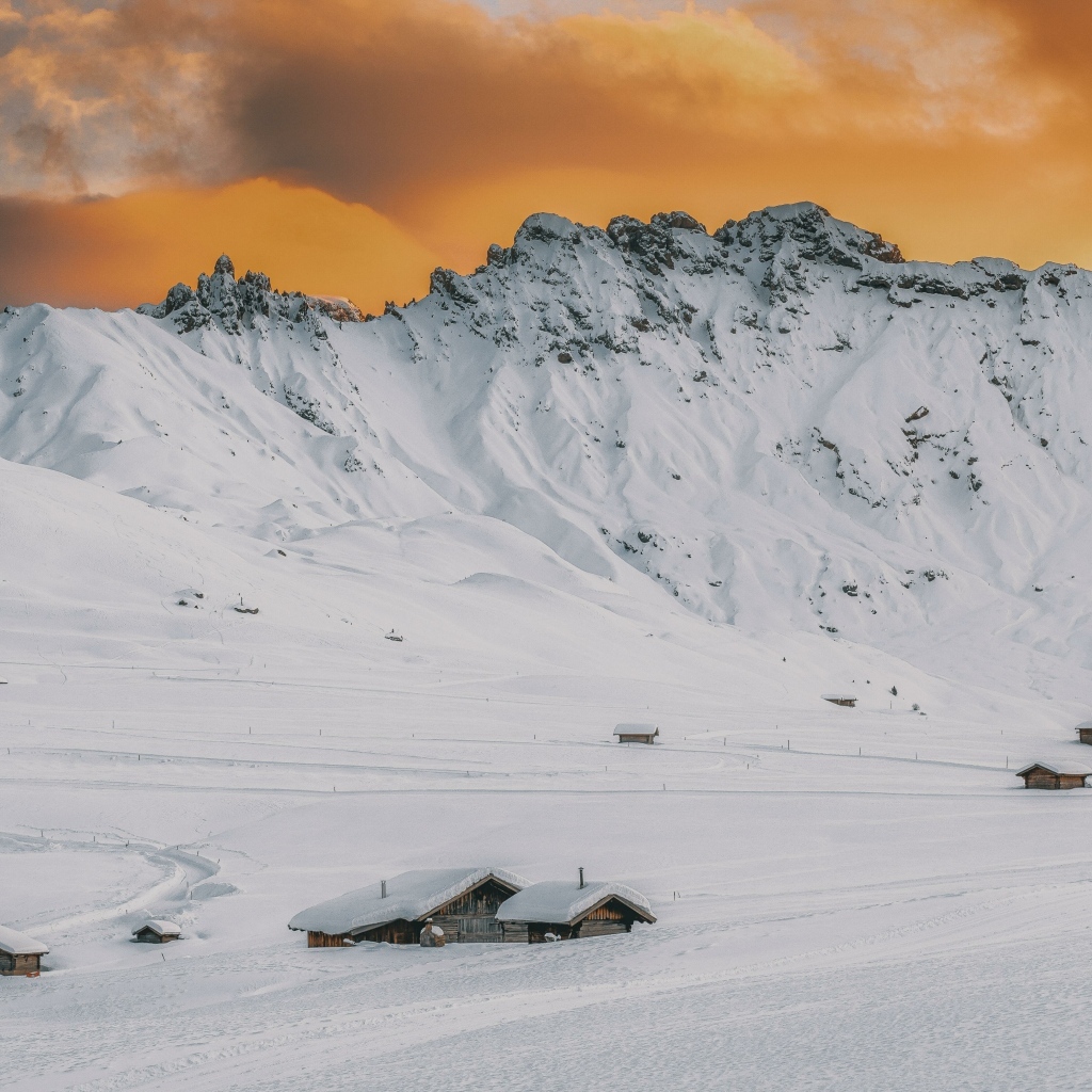 Красивая заснеженная гора под оранжевым небом
