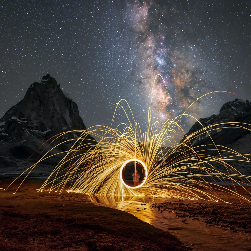 Огненное шоу под ночным красивым небом в горах