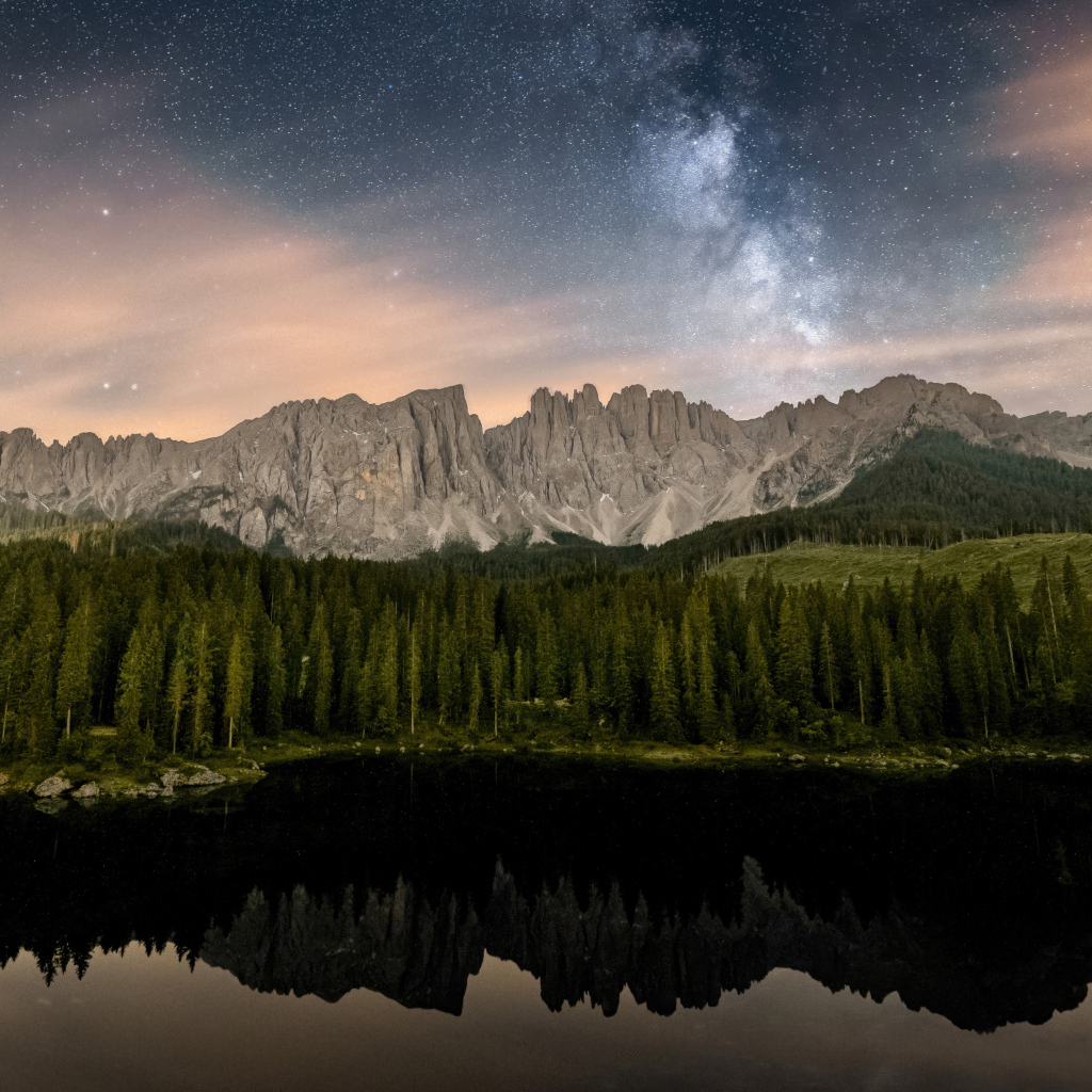Млечный путь над горами и лесом отражающимися в воде