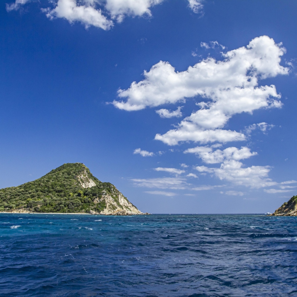 Покрытые зеленью горы в море под голубым небом