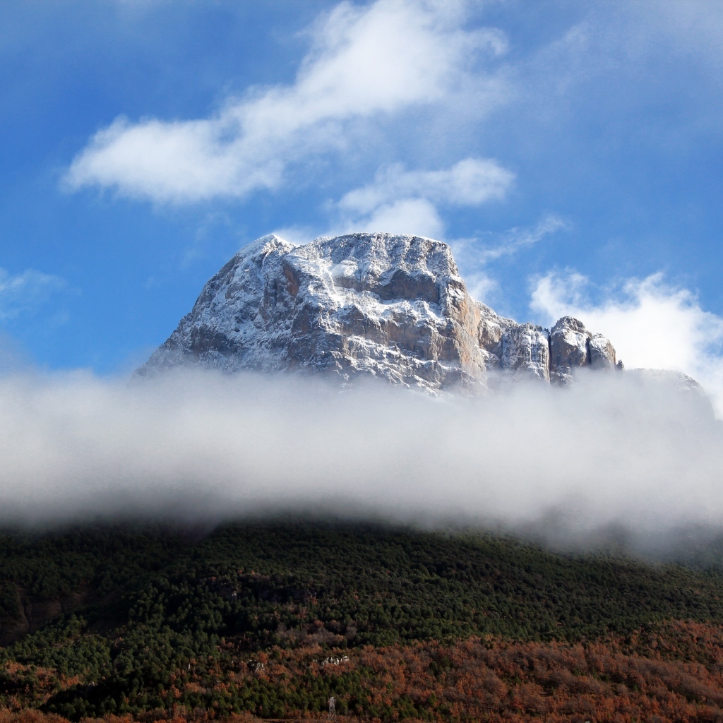 Заснеженная горная вершина в белых облаках
