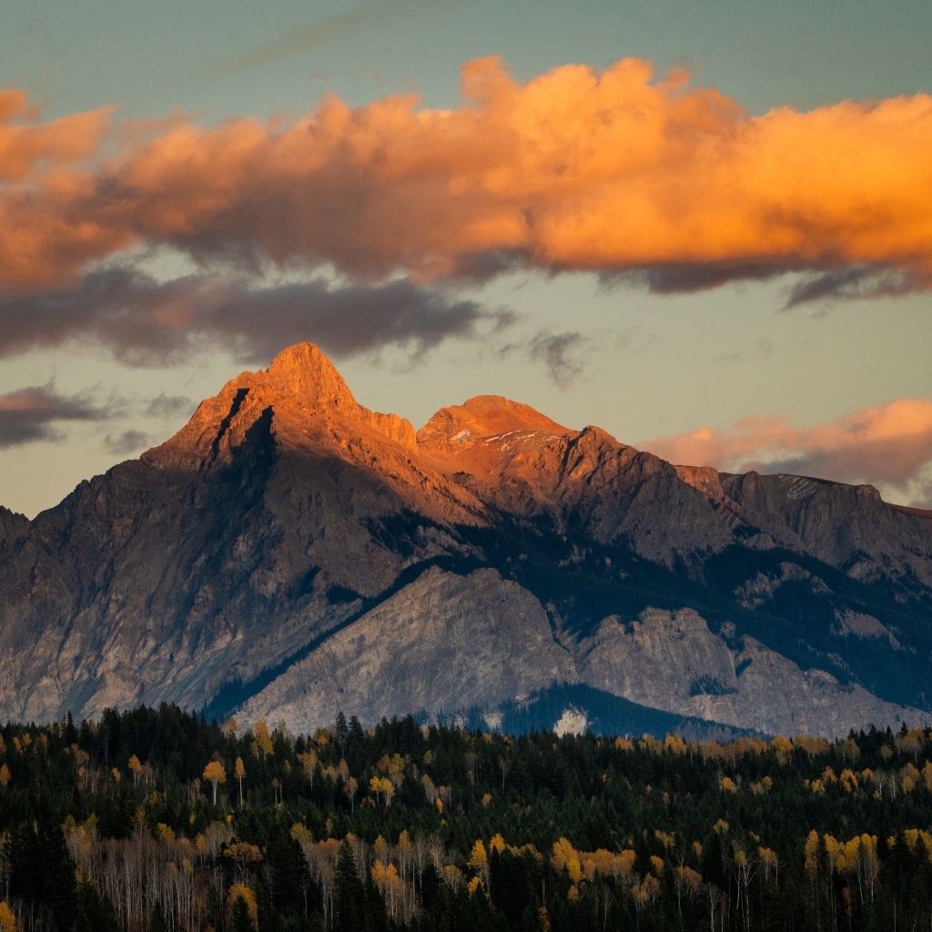 Солнце в облаках освещает вершину горы
