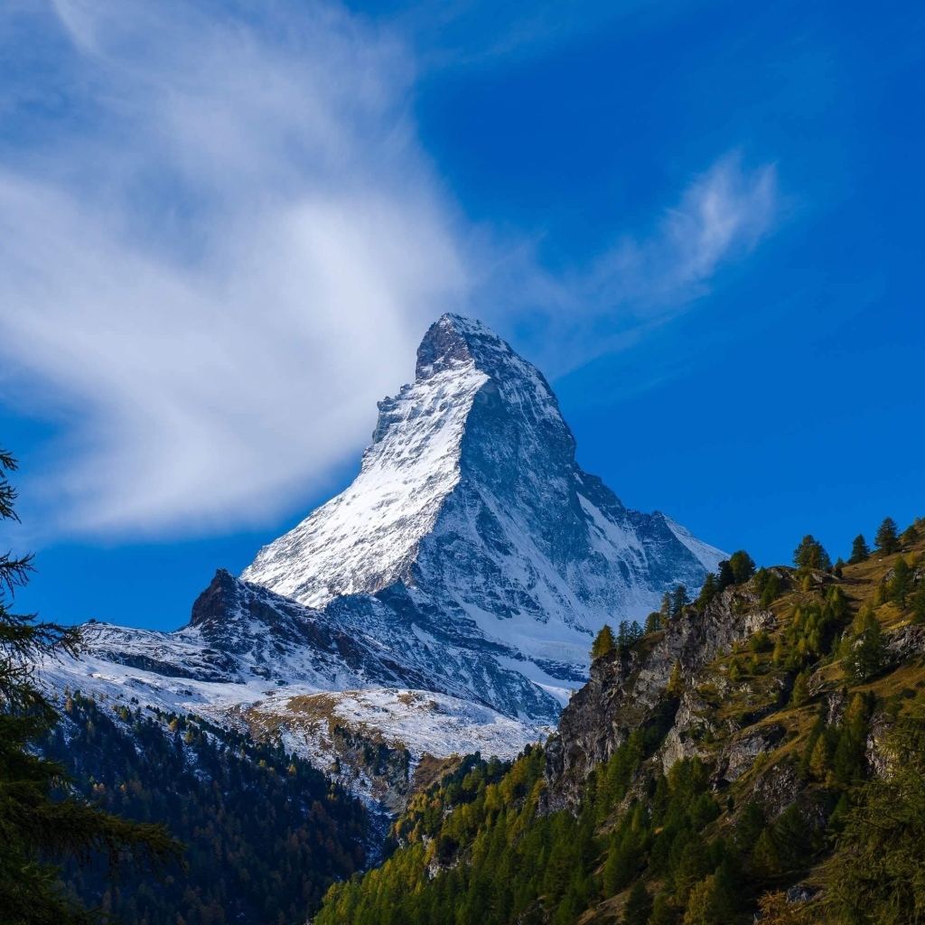 Вид на высокую заснеженную гору под голубым небом